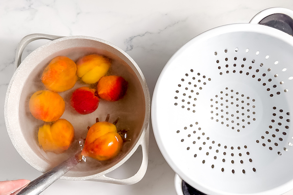 dipping peaches into hot water to loosen skins