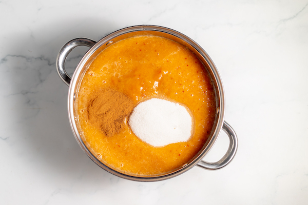 peach puree in a pot with sugar, cinnamon, cloves, and lemon juice