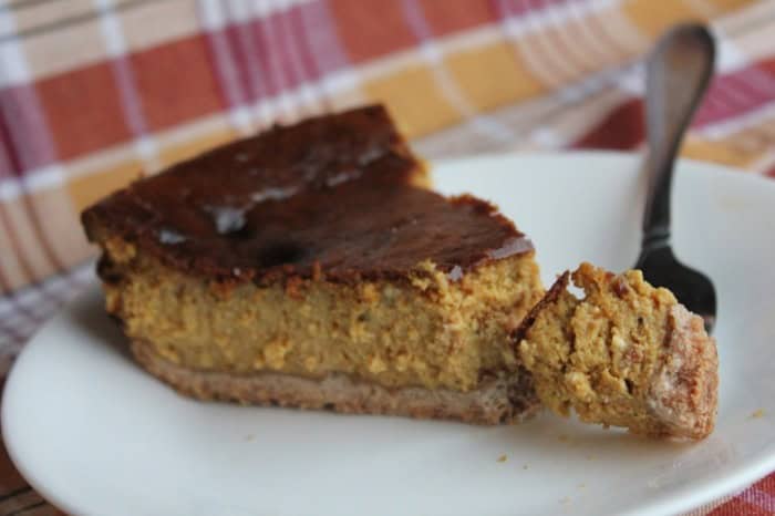 Photo shows a piece of pumpkin cheesecake with a fork on a white plate