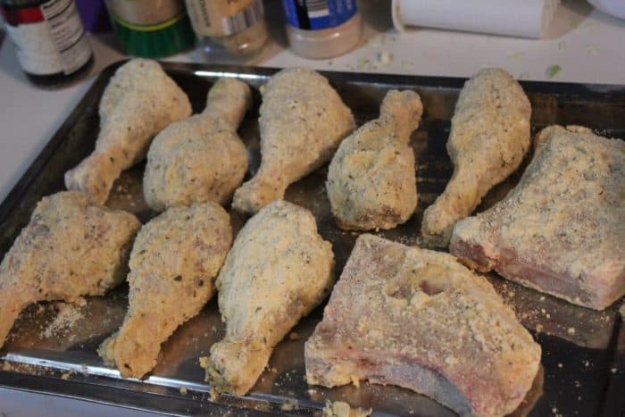 Image shows several pieces of chicken breaded and laid out on a cookie sheet