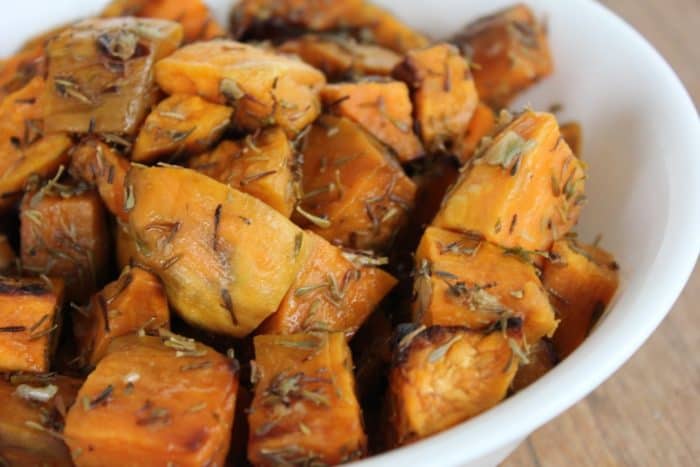 Photo shows a close up of a bowl of garlic thyme roasted sweet potatoes