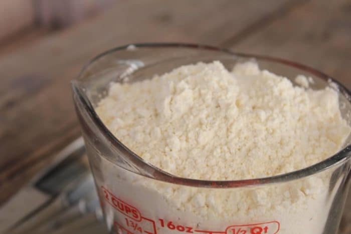 Image shows a glass measuring cup holding gluten free flour mix 