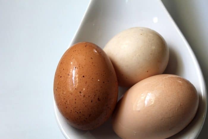 Image shows three eggs sitting in a ceramic spoon