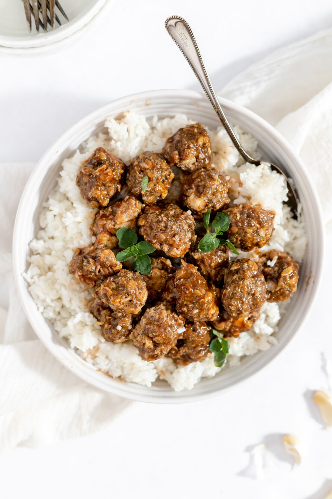 An overhead image of a bowl of homemade gluten-free meatballs served over fluffy white rice.