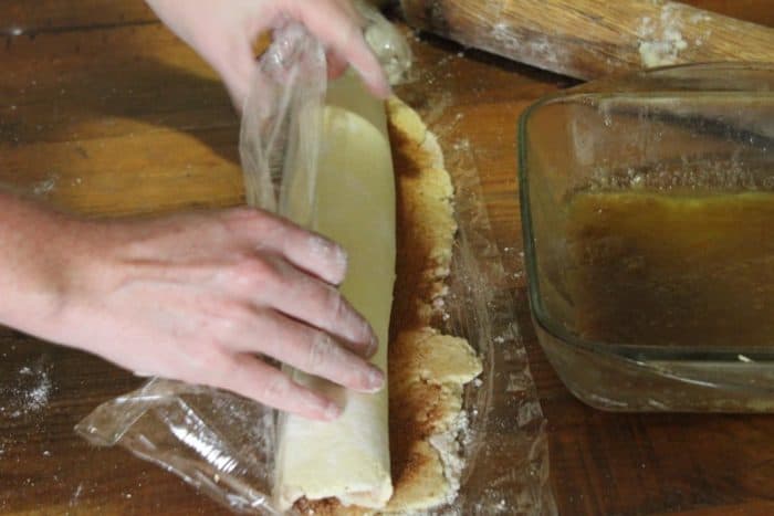 Photo shows hands rolling cinnamon roll dough
