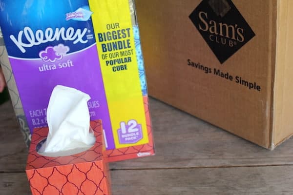 Image shows a Sam's Club box sitting on a table, with a large package of Kleenex sitting next to it.