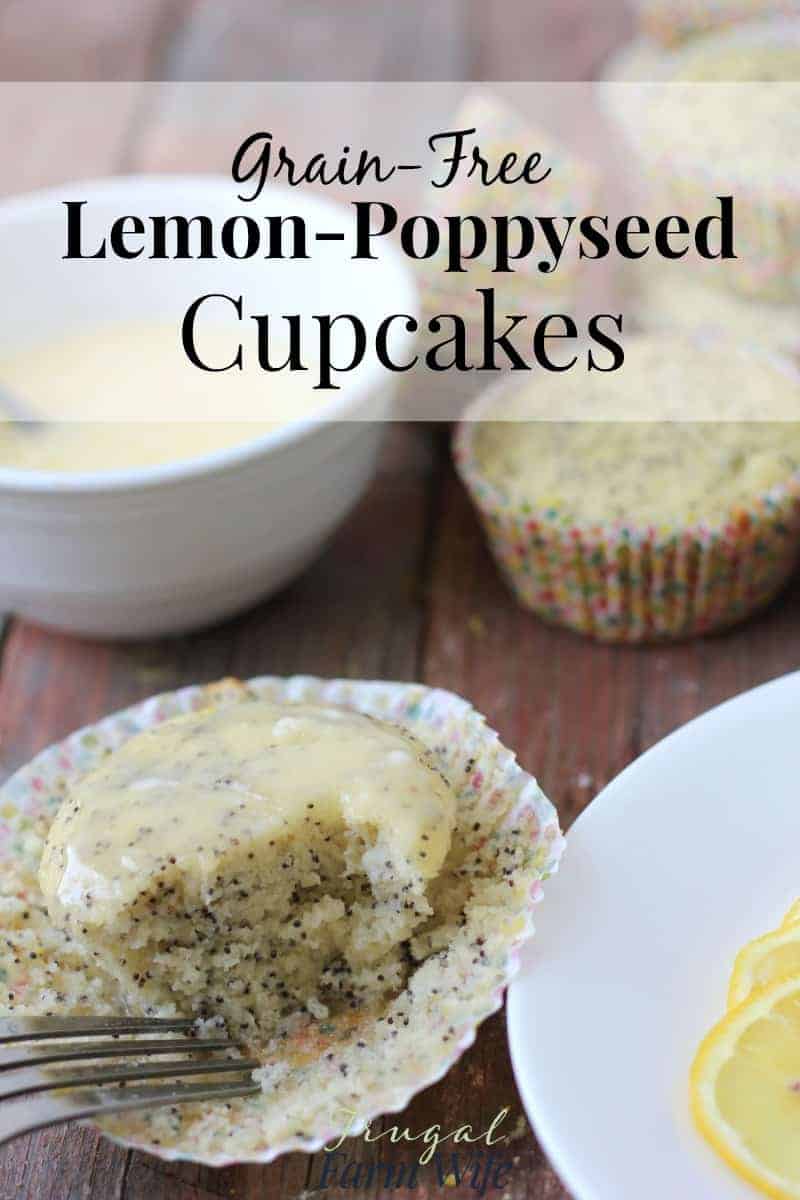 Image shows a lemon poppyseed cupcake sitting inside the paper wrapper it was baked in, with a fork taking a bite from it. There are several more cupcakes and a bowl of icing behind the cupcake. 