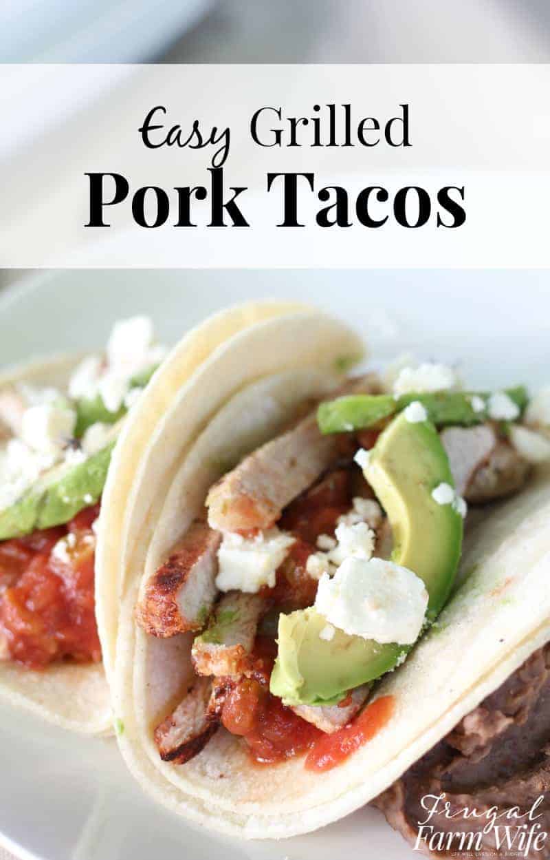 Image shows a close up of two pork tacos with avocado, salsa and cheese. A text overlay reads "Easy Grilled Pork Tacos"