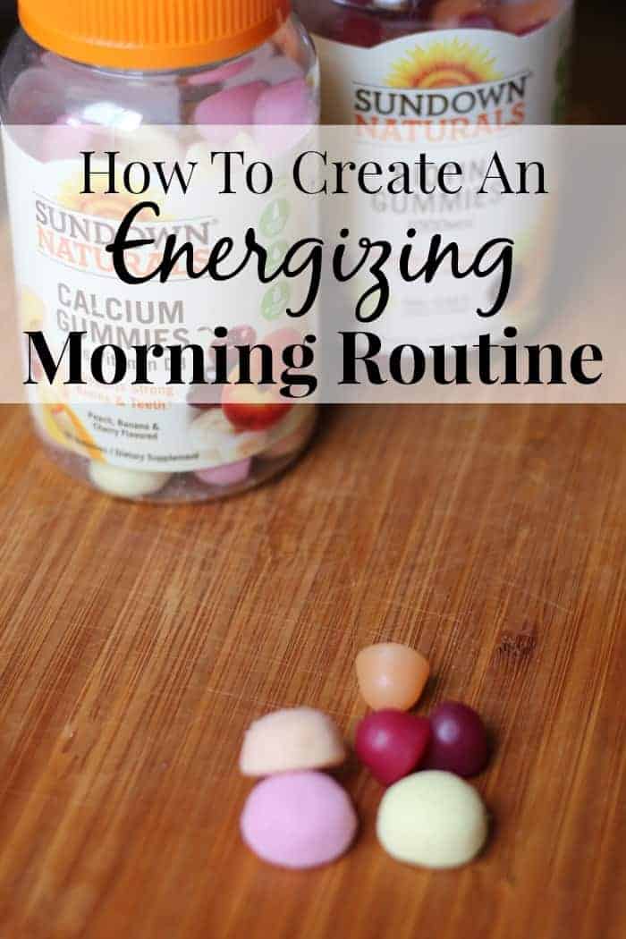 Image shows two bottles of Sundown Vitamins gummies on a wood table, with a handful of gummies sitting nearby. Text overlay reads "How to Create an Energizing Morning Routine"