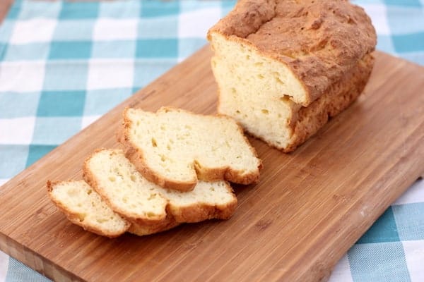 Photo shows a loaf of bread with a few slices cut off, on a wooden cutting board