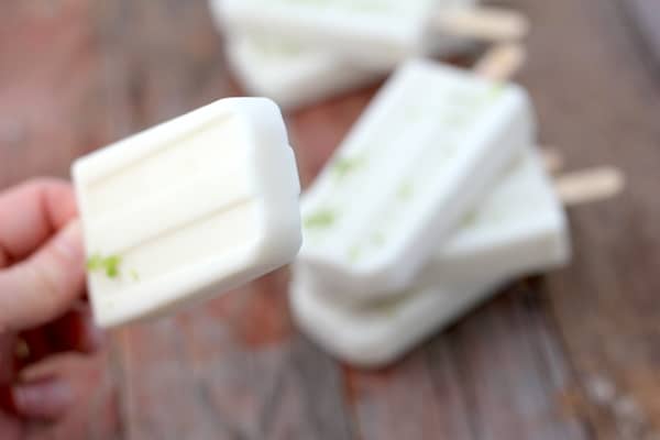 Photo shows a hand holding a popsicle, with more popsicles on the table 