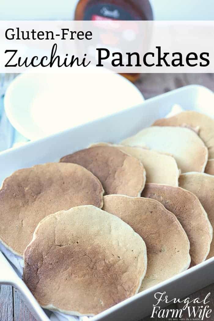 Image shows a white casserole pan full of gluten free zucchini pancakes stacked on one another. Text overlay reads "Gluten-Free Zucchini Pancakes"