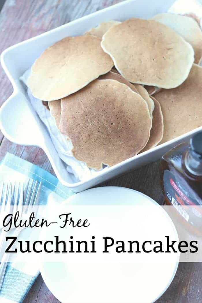 Image shows a white casserole pan full of gluten free zucchini pancakes stacked on one another. Text overlay reads "Gluten-Free Zucchini Pancakes"