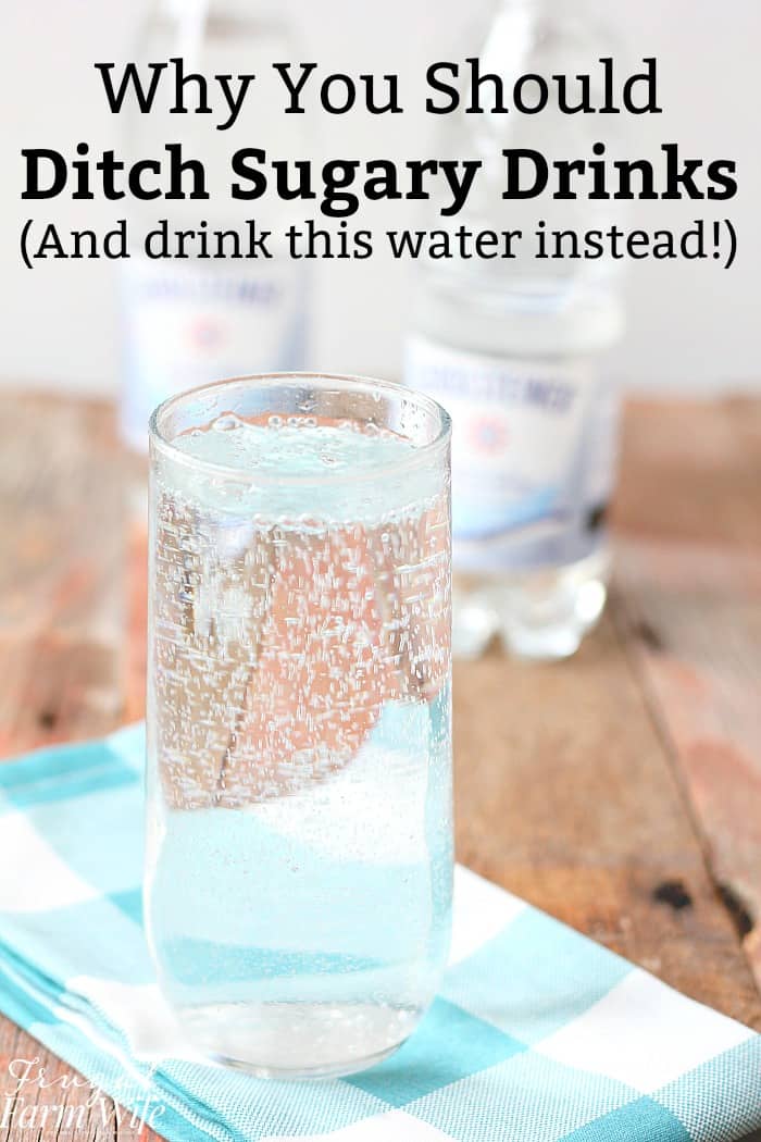 Image shows a tall glass of water on a napkin on a table with text overlay that reads "Why You Should Ditch Sugary Drinks (And drink water instead!)