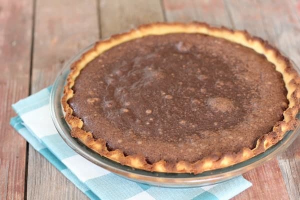 Photo shows a pie sitting on a table and blue and white napkin