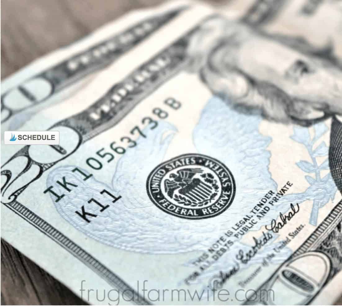 Image shows a close up of two $20 bills laying on a wood table.