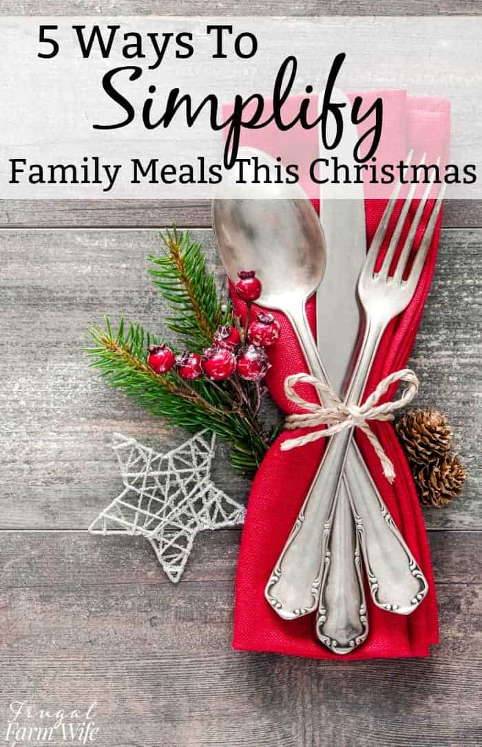 Image shows a table setting of silverware on a red napkin, tied with a string on a table. Text above reads "5 Ways to Simplify Family Meals This Christmas"