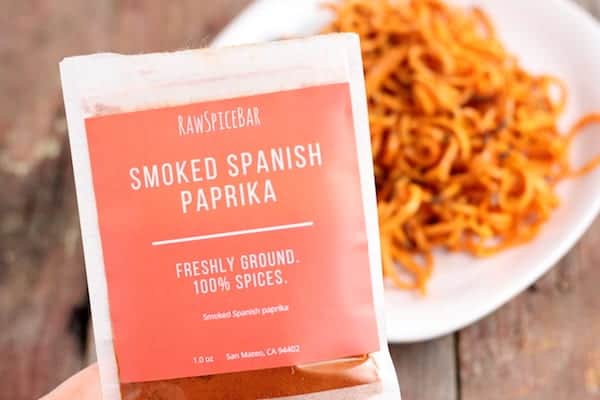 Image shows a seasoning packet of smoked Spanish paprika with a plate of curly fries in the background