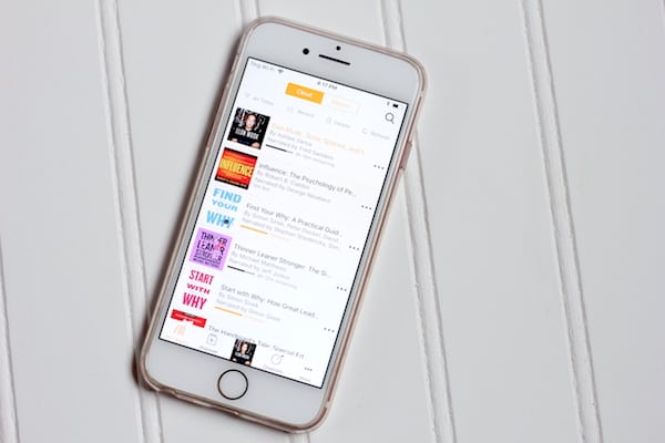Image shows a cell phone laid on a white table, with its screen open to Audible to listen to audio books.