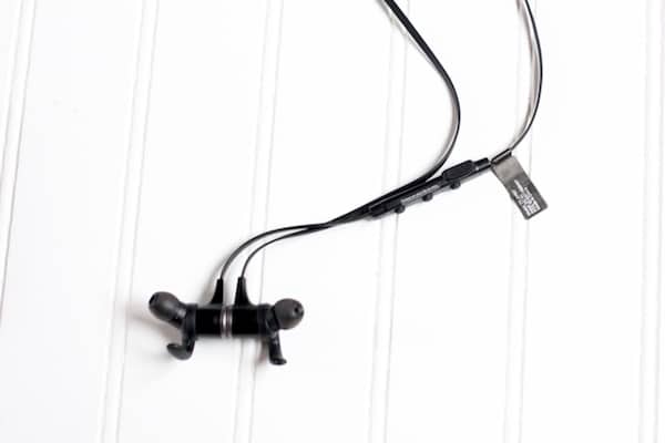 Image shows black Tao Traonics earbuds laying on a white table.