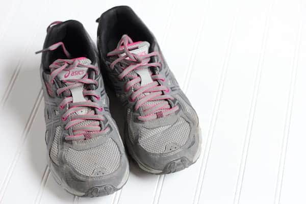 Image shows a pair of grey Asics running shoes on a white surface