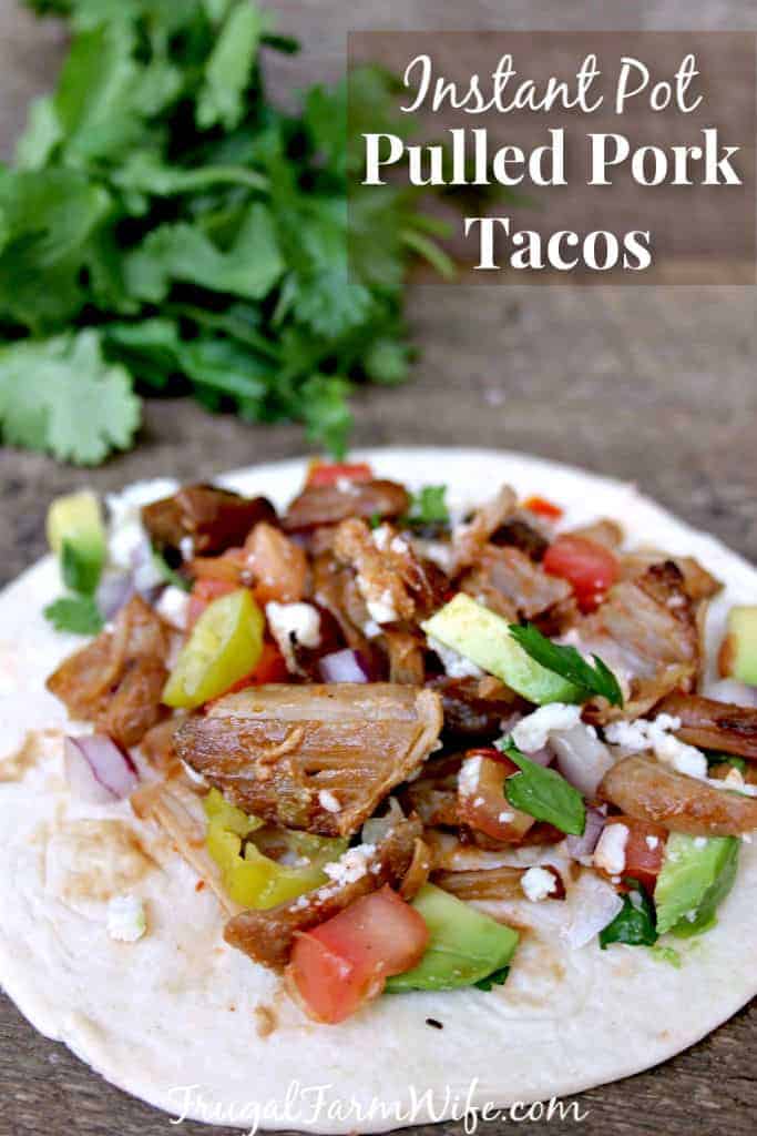 Image shows a close up of a pulled pork taco with text that reads "Instant Pot Pulled Pork Tacos"