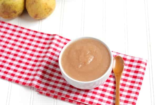 Image shows a bowl of pear sauce sitting on a napkin with a spoon