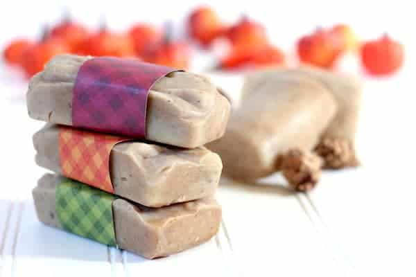 Image shows a stack of homemade soaps each wrapped in a different color paper on a white surface.