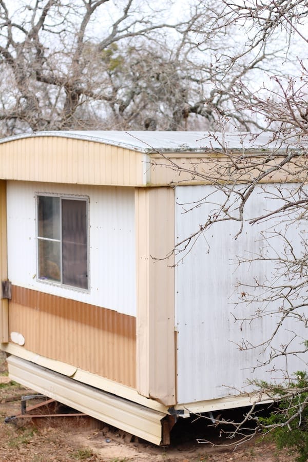 Image shows an exterior shot of the mobile home surrounded by trees