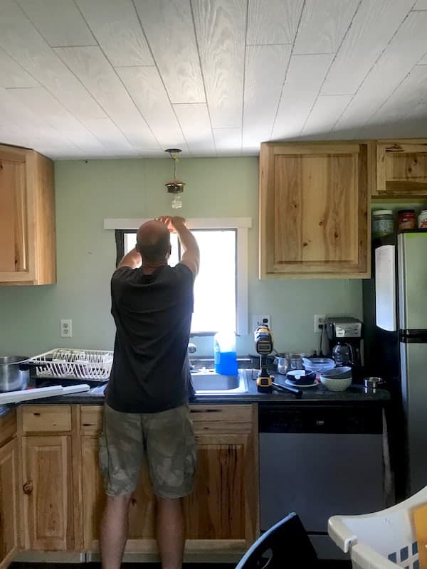 Image shows a man installing trim around a window in the mobile home