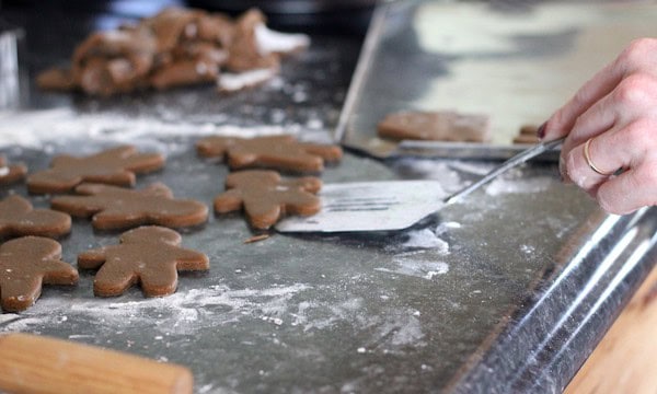 Image shows a spatula picking up an uncooked gingerbread man cookie