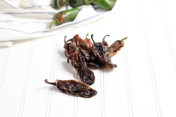 A pile of dried chipotle peppers sit on a white counter top