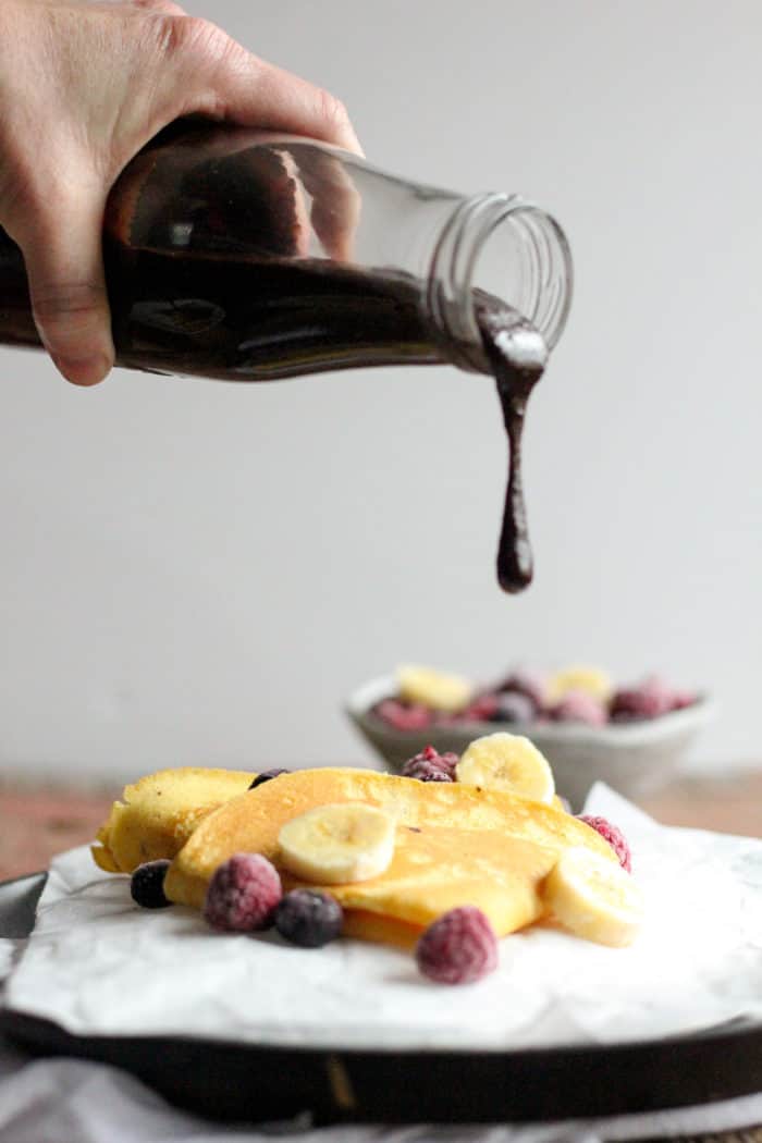 Photo shows a plate of crepes with a bottle of chocolate sauce being poured onto them