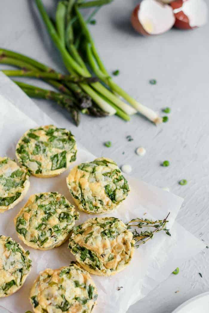 Image shows several vegetable egg bites next to some green onions
