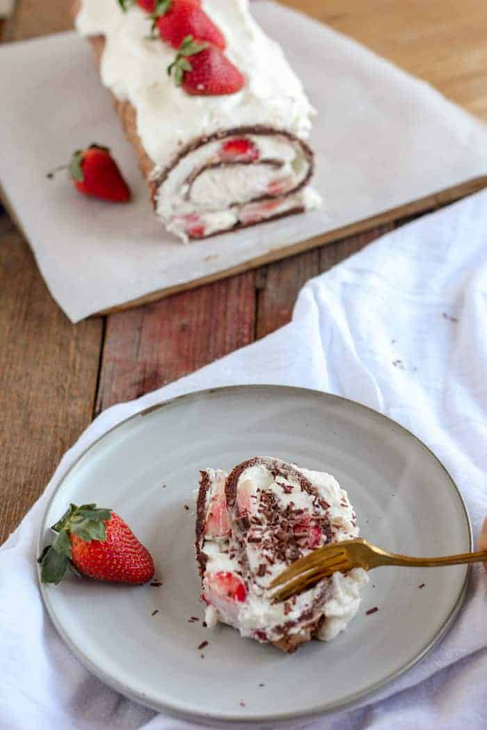 Photo shows a plate of pavlova roulade next to a plate with a slice of it