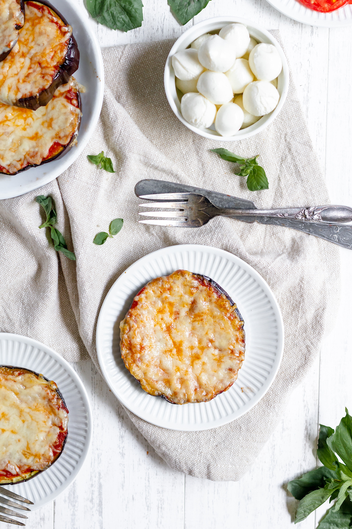 Photo shows a low-carb eggplant pizza on a small plate with a knife and fork nearby