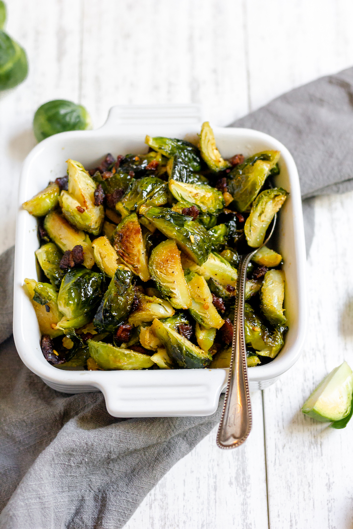 Image shows a pan of roasted brussels sprouts with a spoon