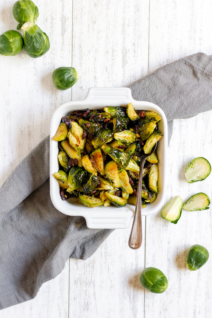 Image shows a pan of roasted brussels sprouts photographed from above on a table