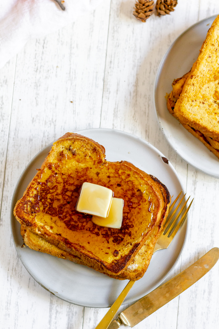 Photo shows two plates of French Toast from above, one with butter and syrup