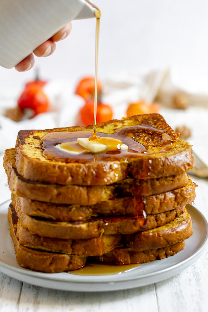 Image shows a stack of pumpkin spice French Toast with syrup being poured over it