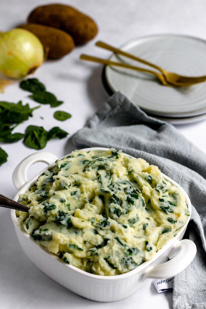 Image shows a dish of spinach and mashed potatoes on a table
