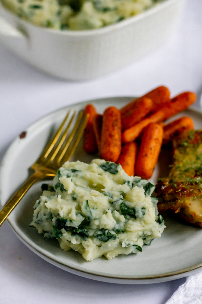 Image shows a dinner plate with roasted carrots, mashed potatoes and a fork