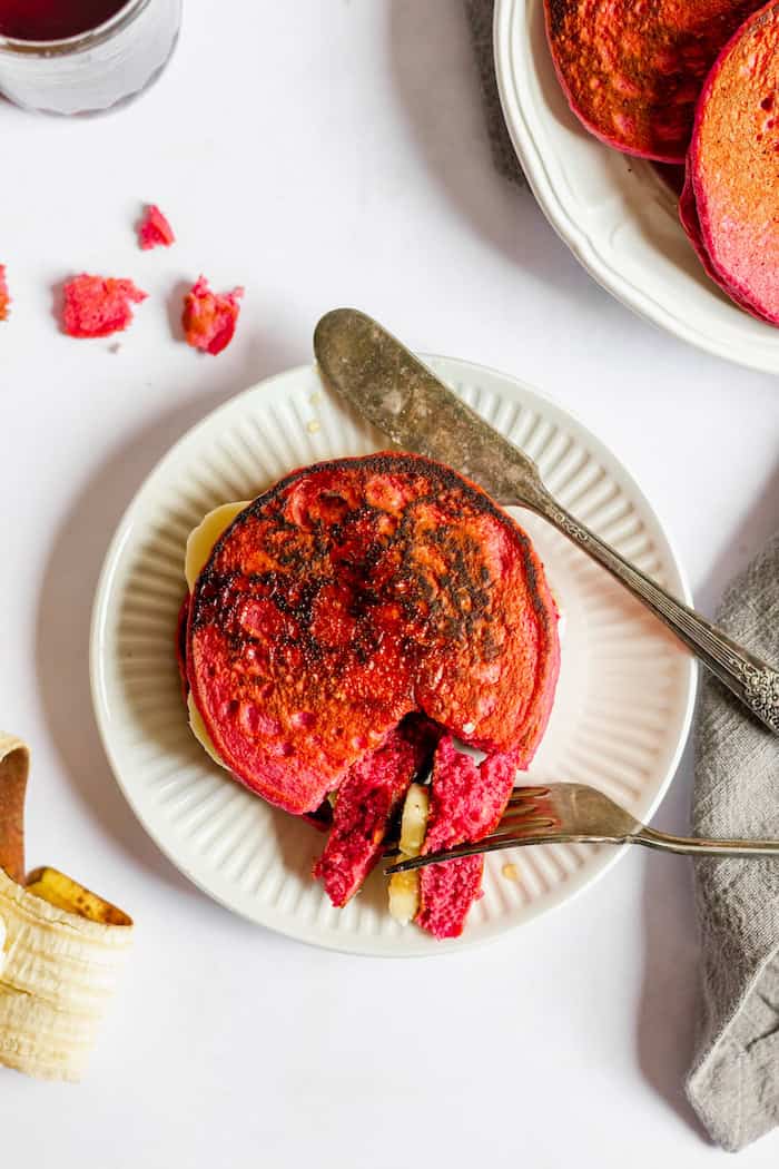Image shows a plate of pink beet pancakes photographed from above