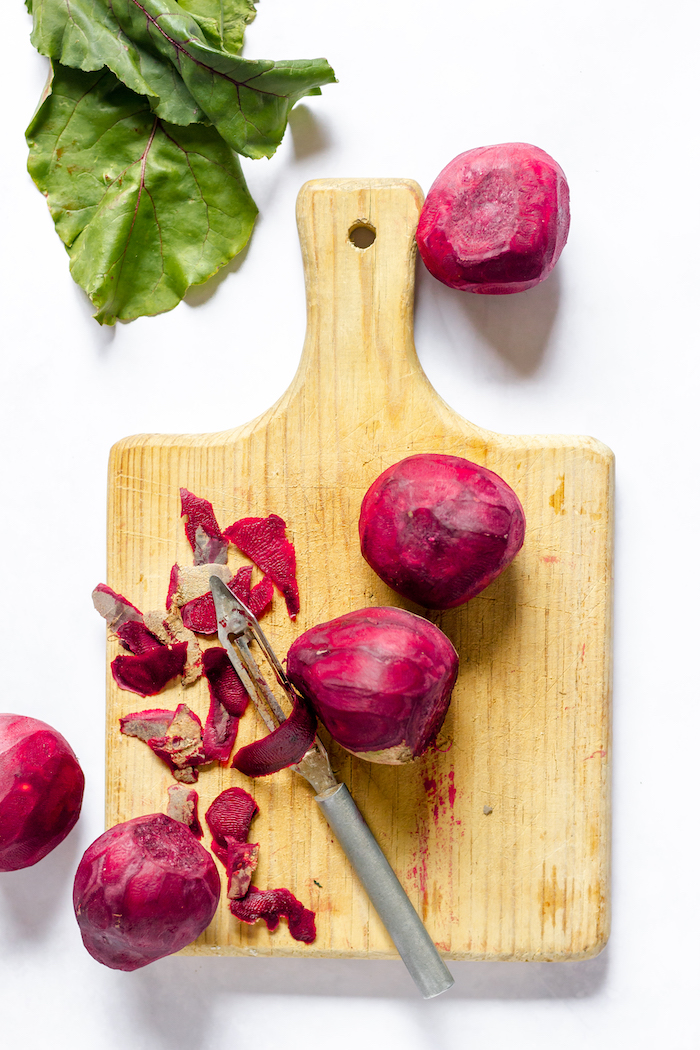 Image, taken from above, shows several beets on a cutting board, after they were peeled.