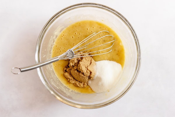 Image, taken from above shows a glass mixing bowl with sugars added to the banana cupcake batter, ready to be whisked in.