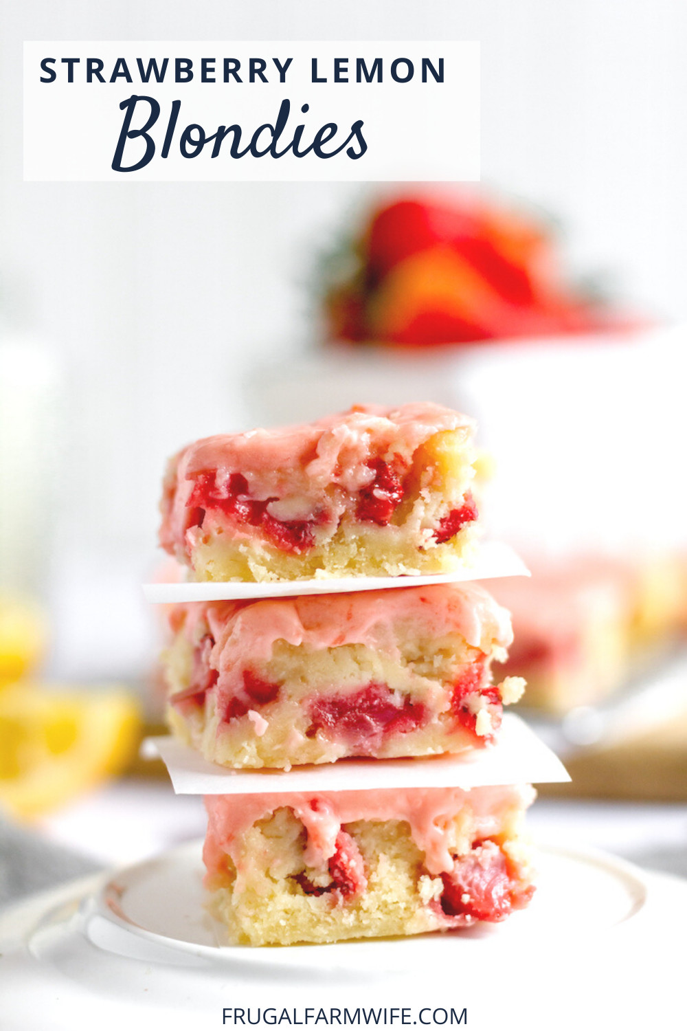 Photo shows a stack of strawberry lemon blondies on a plate, separated by a piece of white paper.  Blurred in the background are red strawberries and yellow lemons. Text overlay reads "Strawberry Lemon Blondies"