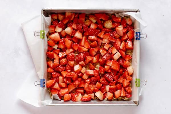 Image, taken from above, shows strawberries evenly distributed in a square pan. 