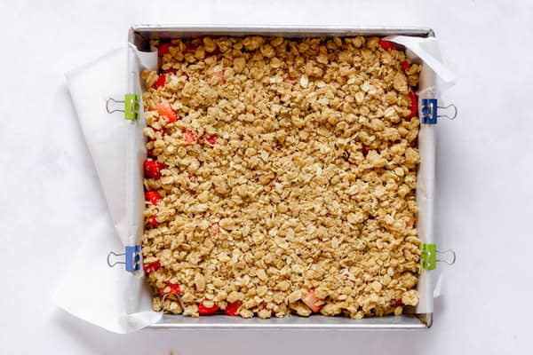 Image, taken from above, shows a square pan with gluten free strawberry oatmeal bars ready to bake. 
