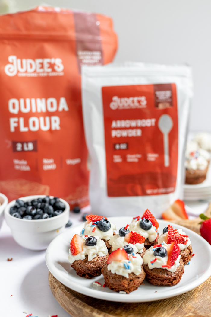 Image shows a plate of gluten free brownie bites on a plate with Judee's gluten free flours in the background