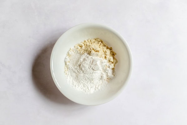 Image, taken from above, shows a white mixing bowl with the dry ingredients for gluten free brownie bites